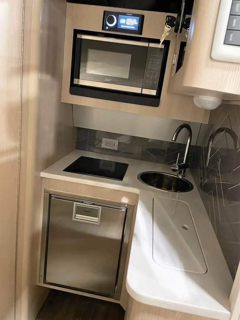 Slide: The Image of Compact kitchen area in 2025 Scout 400 LXF boat with microwave, sink, and mini-fridge. - 22