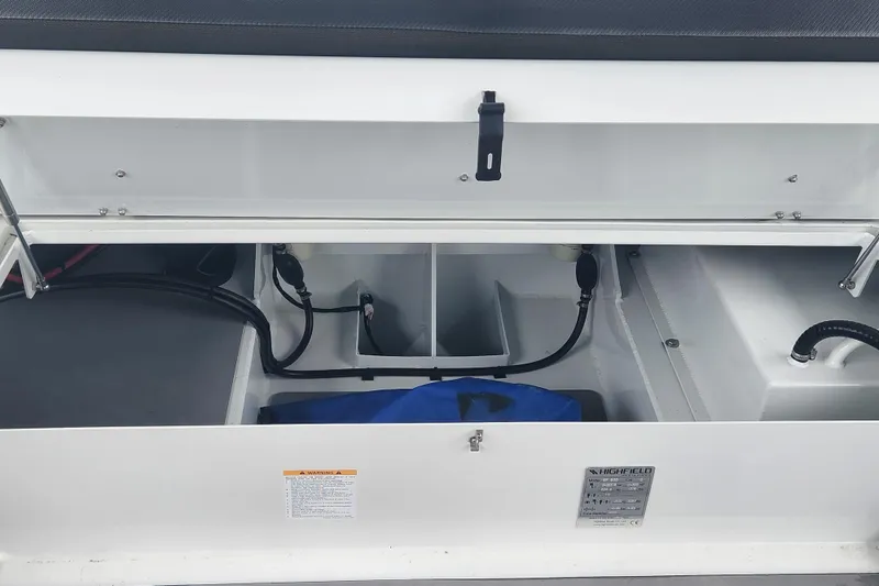 Slide: The Image of 2023 Highfield Sport 900 boat storage compartment with cables and blue bag. - 13