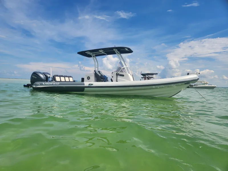 Slide: The Image of 2023 Highfield Sport 900 boat on calm green water under blue sky. - 2