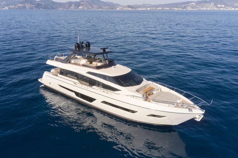 Slide: The Image of 2024 Ferretti Yachts 780 cruising on open water with coastal mountains in the background. - 26