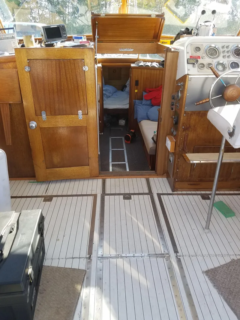 Slide: The Image of 1962 Chris-Craft Roamer interior with wooden cabinetry, steering wheel, and cozy sleeping area. - 4