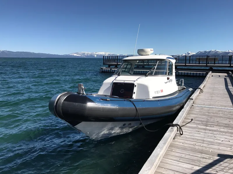 Slide: The Image of 2003 Protector Targa 28 boat docked on a sunny day with mountains in the background. - 10