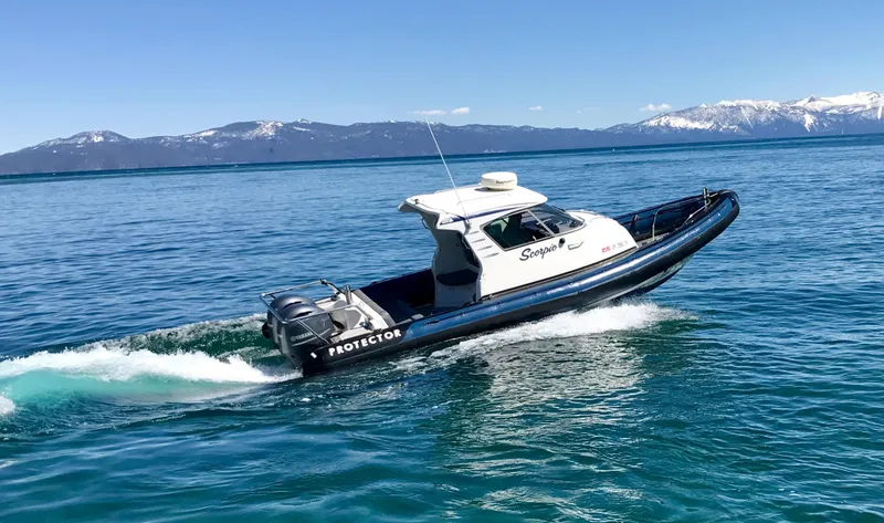 Slide: The Image of 2003 Protector Targa 28 boat cruising on a clear blue lake with mountains in the background. - 3