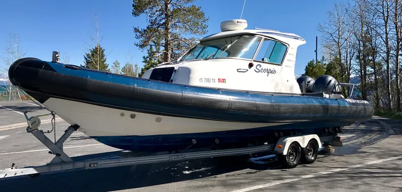 Slide: The Image of 2003 Protector Targa 28 boat on trailer, parked outdoors with trees in the background. - 31