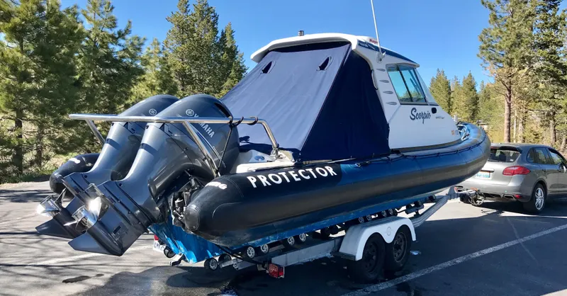 Slide: The Image of 2003 Protector Targa 28 boat on trailer with dual engines, parked in a wooded area. - 33