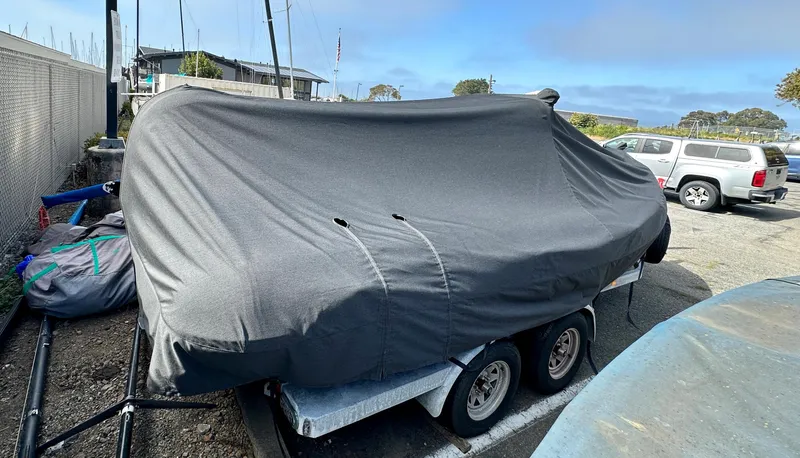 Slide: The Image of 2003 Protector Targa 28 boat covered on a trailer in a parking area. - 37