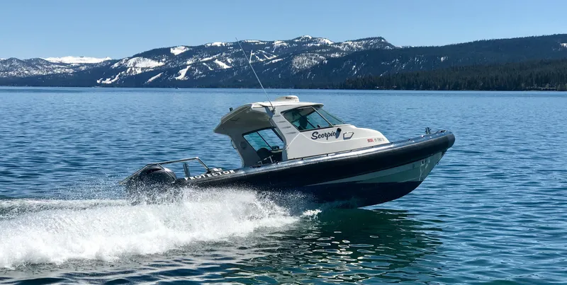 Slide: The Image of 2003 Protector Targa 28 boat cruising on a lake with snowy mountains in the background. - 4