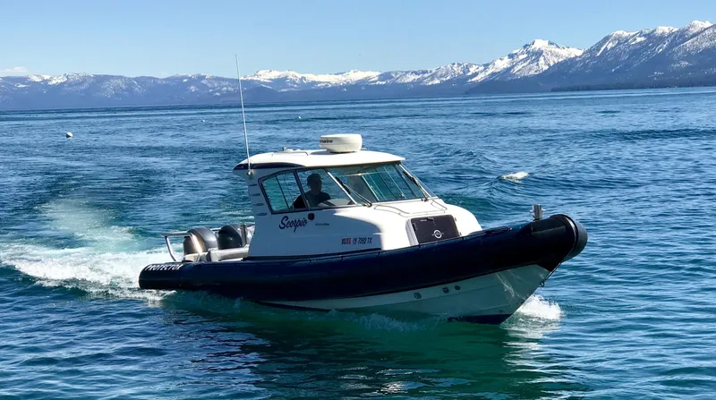 Slide: The Image of 2003 Protector Targa 28 boat cruising on a scenic lake with snowy mountains. - 6