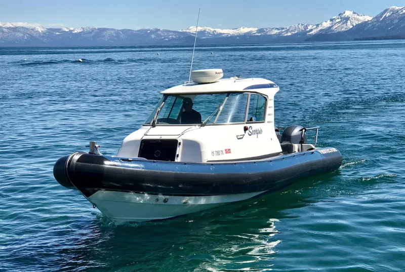 Slide: The Image of 2003 Protector Targa 28 boat on a serene lake with snowy mountains in the background. - 7