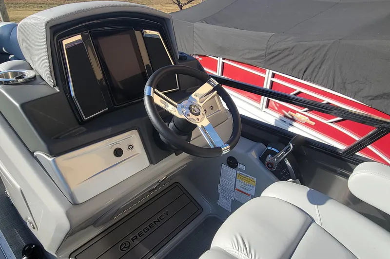 Slide: The Image of 2023 Regency 230 LE3 Sport boat cockpit with steering wheel and control panel. - 5