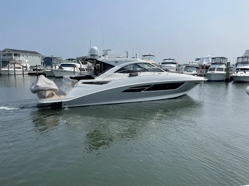 Slide: The Image of A 2018 Sea Ray Sundancer 510 cruising through a calm harbor with several boats in the background. - 8