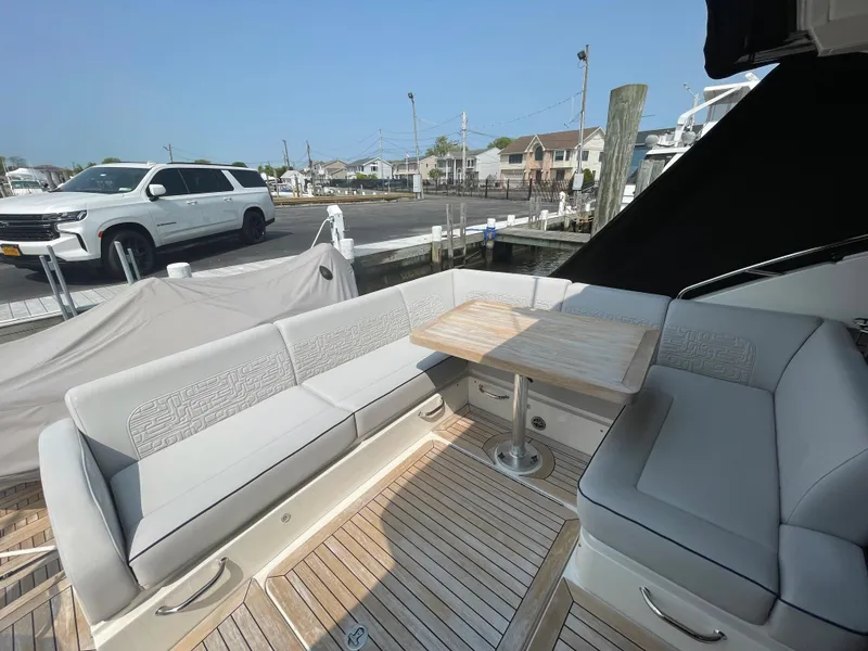 Slide: The Image of The 2018 Sea Ray Sundancer 510 features an elegant seating area with a wooden table on a teak deck. - 42