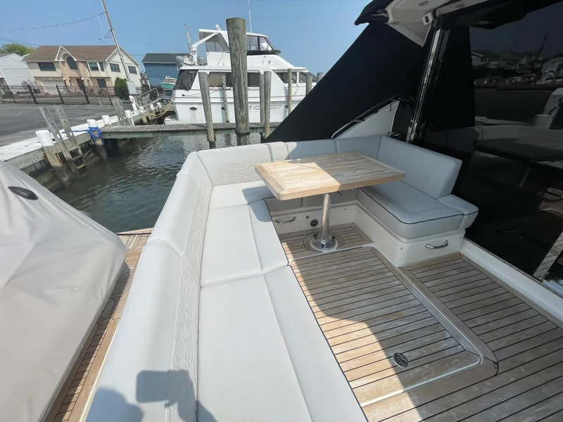 Slide: The Image of The 2018 Sea Ray Sundancer 510 features an elegant seating area with a wooden table and cushioned benches. - 40