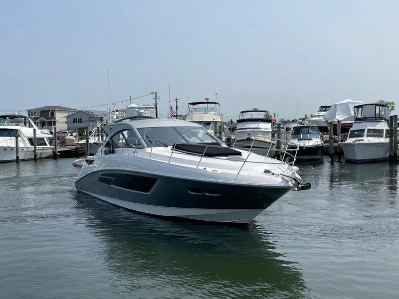 Slide: The Image of A 2018 Sea Ray Sundancer 510 cruising through a busy marina with several boats. - 16