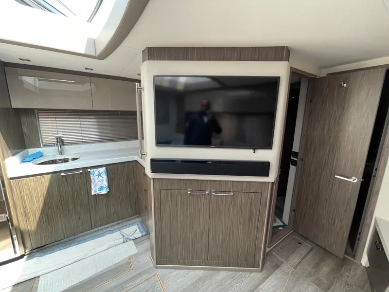 Slide: The Image of Interior of a 2018 Sea Ray Sundancer 510 with modern kitchen and large TV. - 59