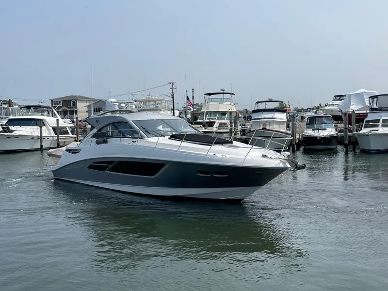 Slide: The Image of A 2018 Sea Ray Sundancer 510 is in the water, surrounded by other boats in the marina. - 15