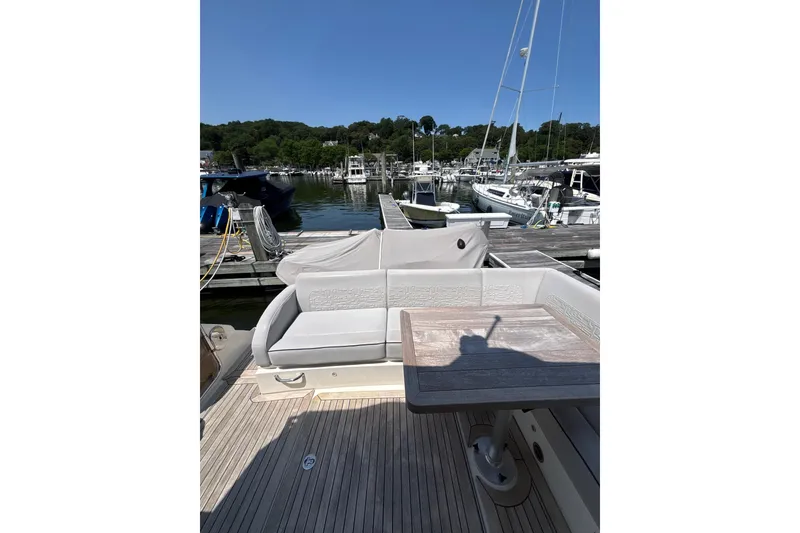 Slide: The Image of 2018 Sea Ray Sundancer 510 yacht docked, featuring elegant seating and a wooden table. - 110