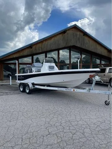Slide: The Image of 2023 NauticStar 215 Bay boat on a trailer outside a rustic building. - 1