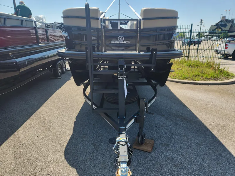 Slide: The Image of 2023 Regency 230 LE3 pontoon boat on a trailer in a parking lot. - 1
