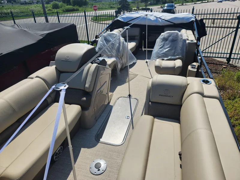 Slide: The Image of 2023 Regency 230 LE3 pontoon boat with beige seating and protective covers. - 6