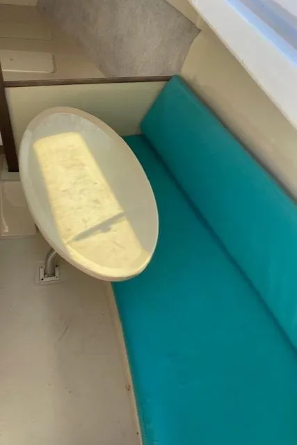 Slide: The Image of Interior of a 1993 Hunter 23.5 sailboat with teal seating and a small table. - 11