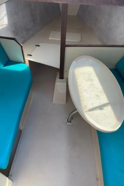 Slide: The Image of Interior cabin of a 1993 Hunter 23.5 sailboat with blue seating and a small table. - 8