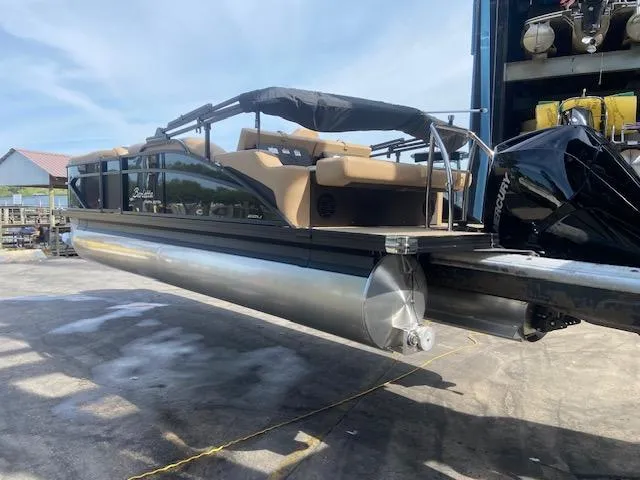 Slide: The Image of 2023 Barletta Cabrio C22U pontoon boat on a lift, featuring tan seating and a black canopy. - 8