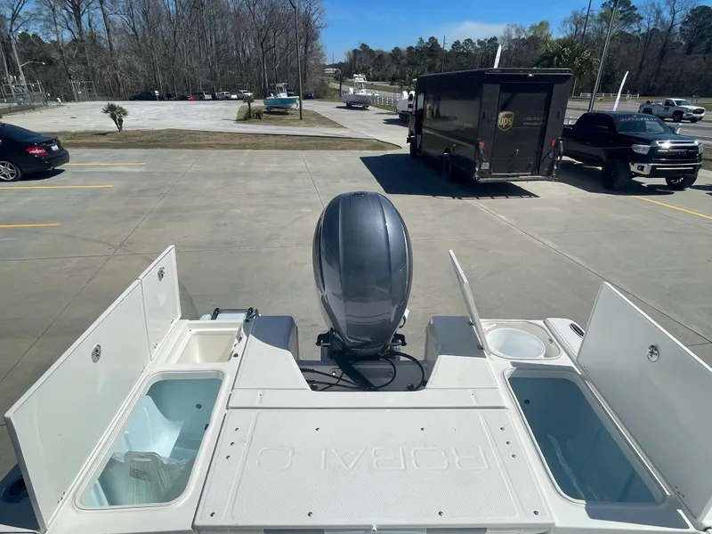 Slide: The Image of 2024 Robalo 226 Cayman boat with open storage compartments and outboard motor. - 9