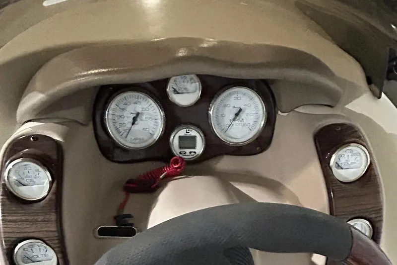Slide: The Image of Dashboard of a 2002 Larson Escape 213 boat with gauges and steering wheel. - 23