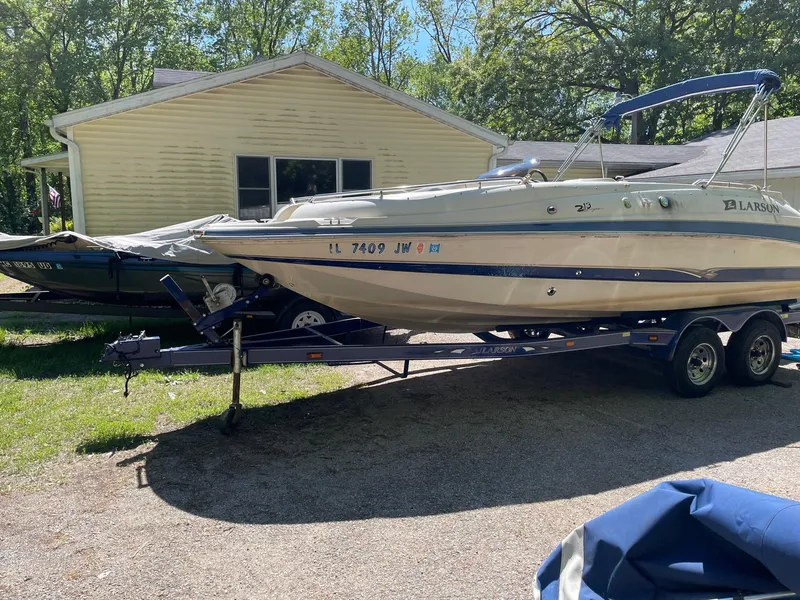 Slide: The Image of 2002 Larson Escape 213 boat on trailer in front of a house. - 3