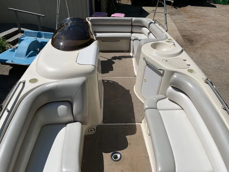 Slide: The Image of 2002 Larson Escape 213 boat interior with white seating and beige flooring. - 6