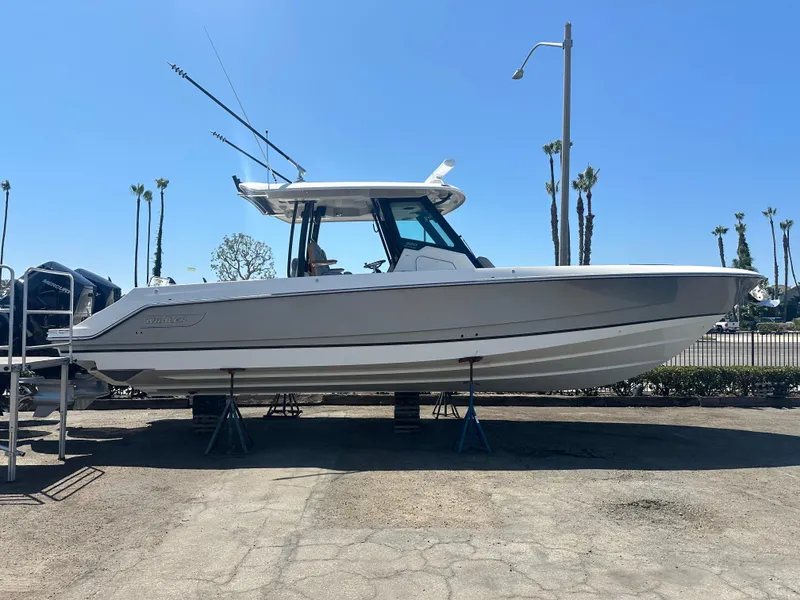Slide: The Image of 2025 Boston Whaler 360 Outrage boat on display, side view, outdoors. - 2
