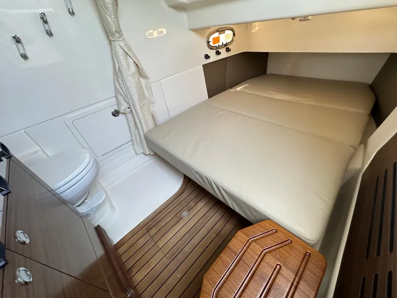 Slide: The Image of 2025 Boston Whaler 360 Outrage cabin with bed, toilet, and wooden flooring. - 22