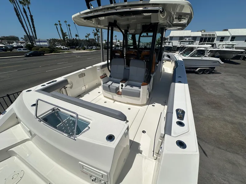 Slide: The Image of 2025 Boston Whaler 360 Outrage boat, spacious deck, modern seating, docked outdoors. - 5