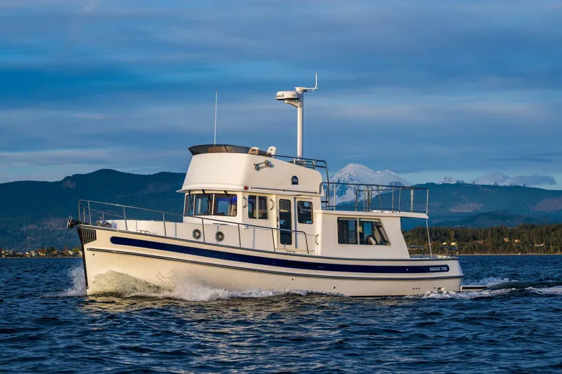 Slide: The Image of 2024 Nordic Tug 40 cruising on a scenic lake with mountains in the background. - 1