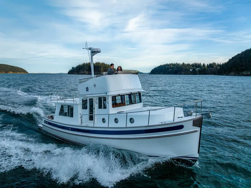 Slide: The Image of 2024 Nordic Tug 40 cruising on open water with scenic background. - 2