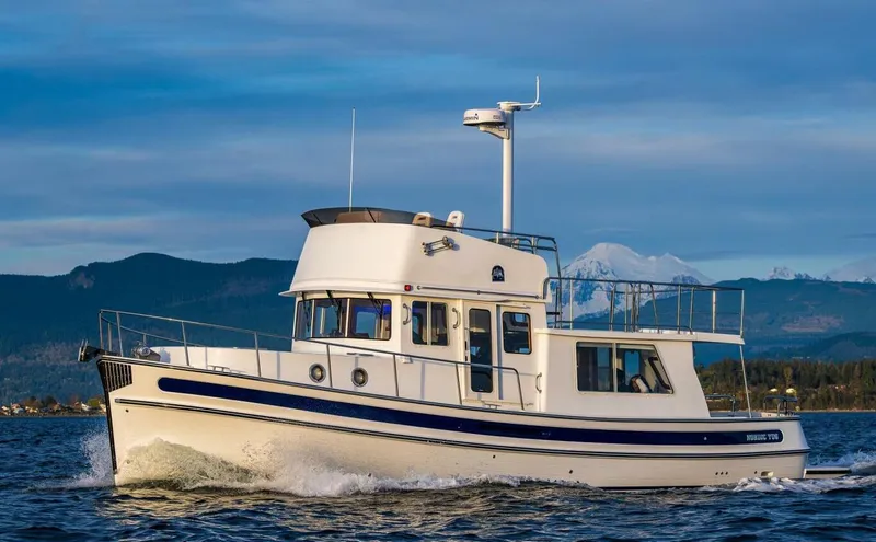 Slide: The Image of 2024 Nordic Tug 40 cruising on scenic waters with mountainous backdrop. - 40