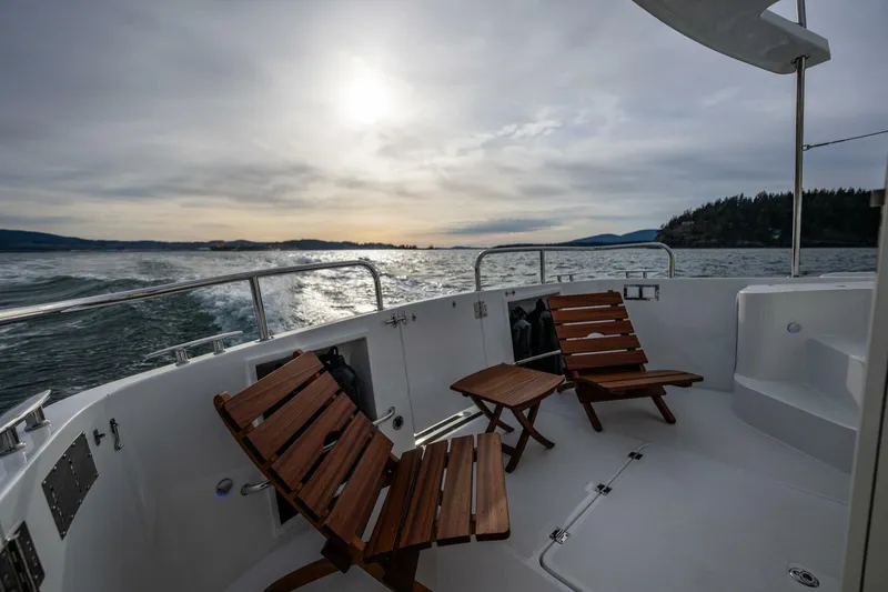Slide: The Image of 2024 Nordic Tug 40 boat deck with wooden chairs, ocean view at sunset. - 8