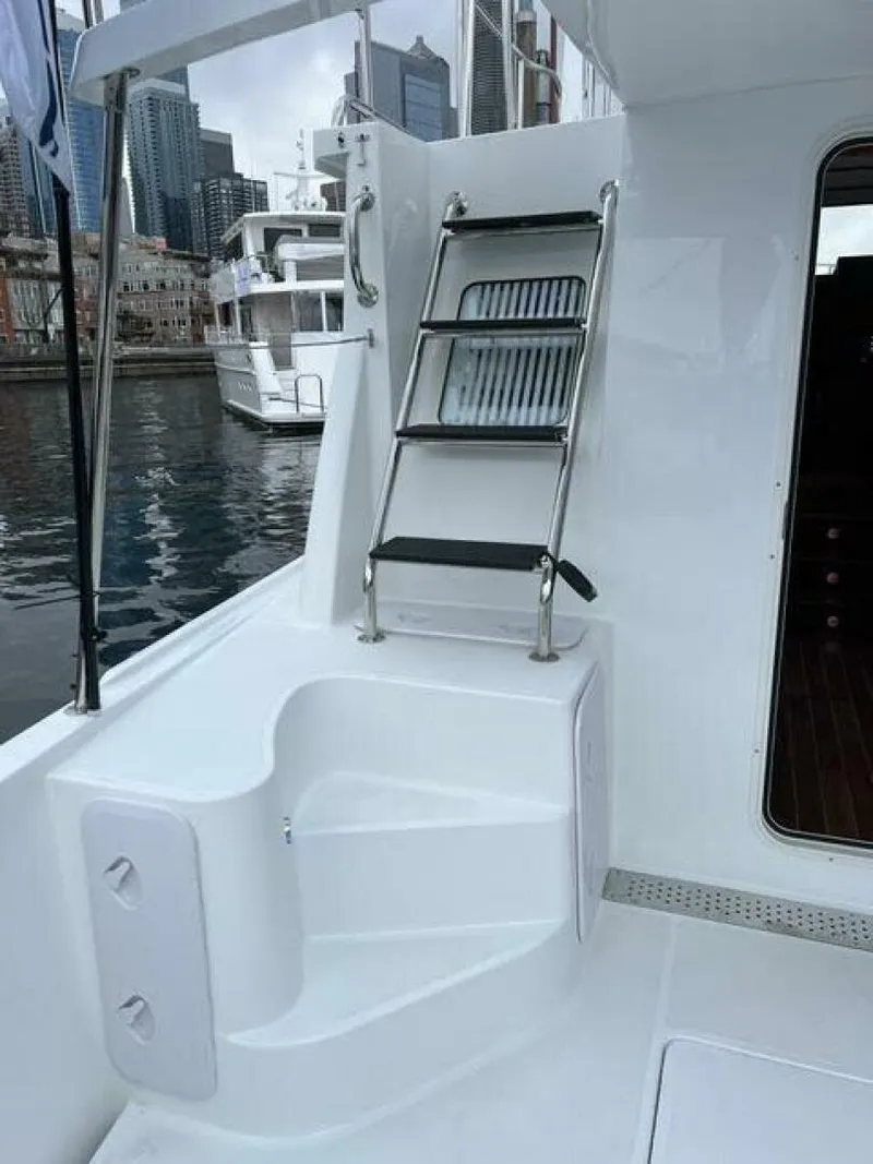 Slide: The Image of 2024 Nordic Tug 40 yacht deck with ladder and cityscape background. - 9