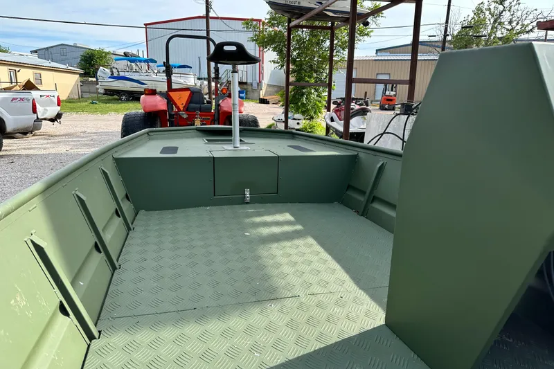 Slide: The Image of 2022 Jon Boat Aluminum Boat, green interior, parked outdoors near industrial buildings. - 8