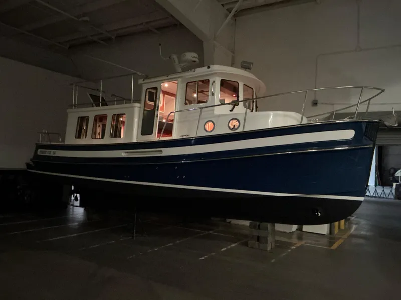 Slide: The Image of 2010 Nordic Tug 32 boat in a dimly lit indoor storage area. - 11