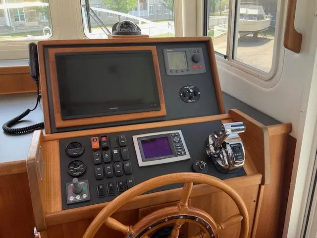 Slide: The Image of Pilothouse of 2010 Nordic Tug 32 with navigation controls and wooden steering wheel. - 13