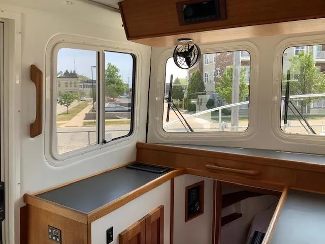 Slide: The Image of Interior of a 2010 Nordic Tug 32, featuring wood cabinetry and large windows. - 19
