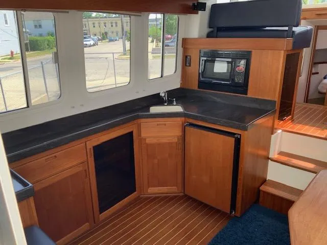 Slide: The Image of Interior of a 2010 Nordic Tug 32, featuring a compact kitchen with wood cabinetry. - 20