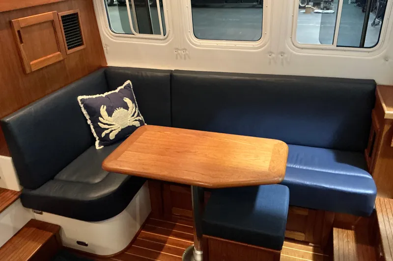 Slide: The Image of Cozy Nordic Tug 32 interior with blue seating, wooden table, and crab-themed pillow, 2010 model. - 22