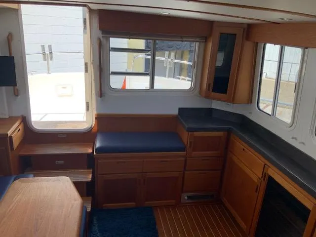 Slide: The Image of Interior of 2010 Nordic Tug 32, featuring wood cabinetry and seating with natural light. - 26