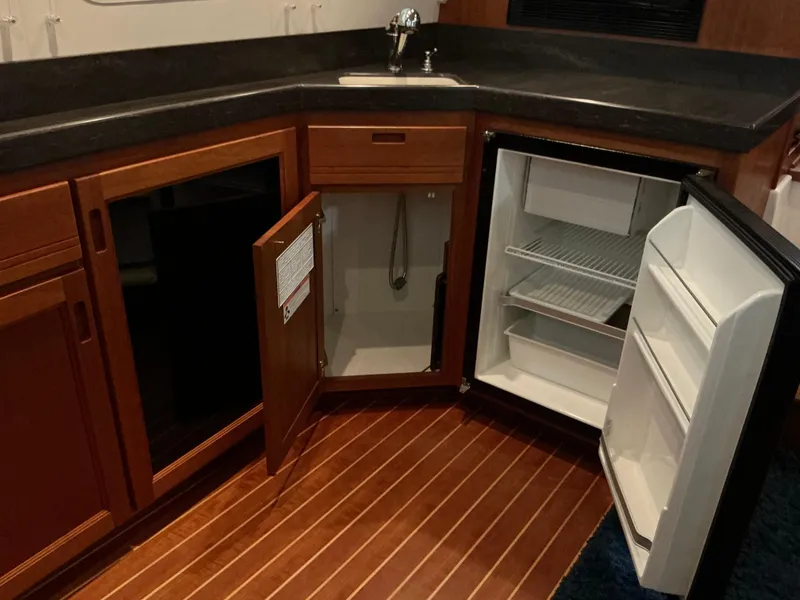 Slide: The Image of Interior of 2010 Nordic Tug 32 showing kitchen with open cabinets and refrigerator. - 28