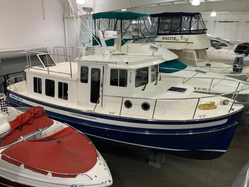 Slide: The Image of 2010 Nordic Tug 32 in a showroom, surrounded by other boats. - 3