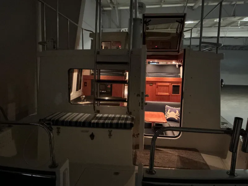 Slide: The Image of Interior view of a 2010 Nordic Tug 32 boat, showcasing cozy seating and wooden cabinetry. - 31