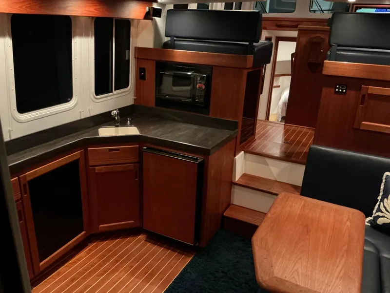 Slide: The Image of Interior of a 2010 Nordic Tug 32, featuring a compact kitchen and dining area. - 33